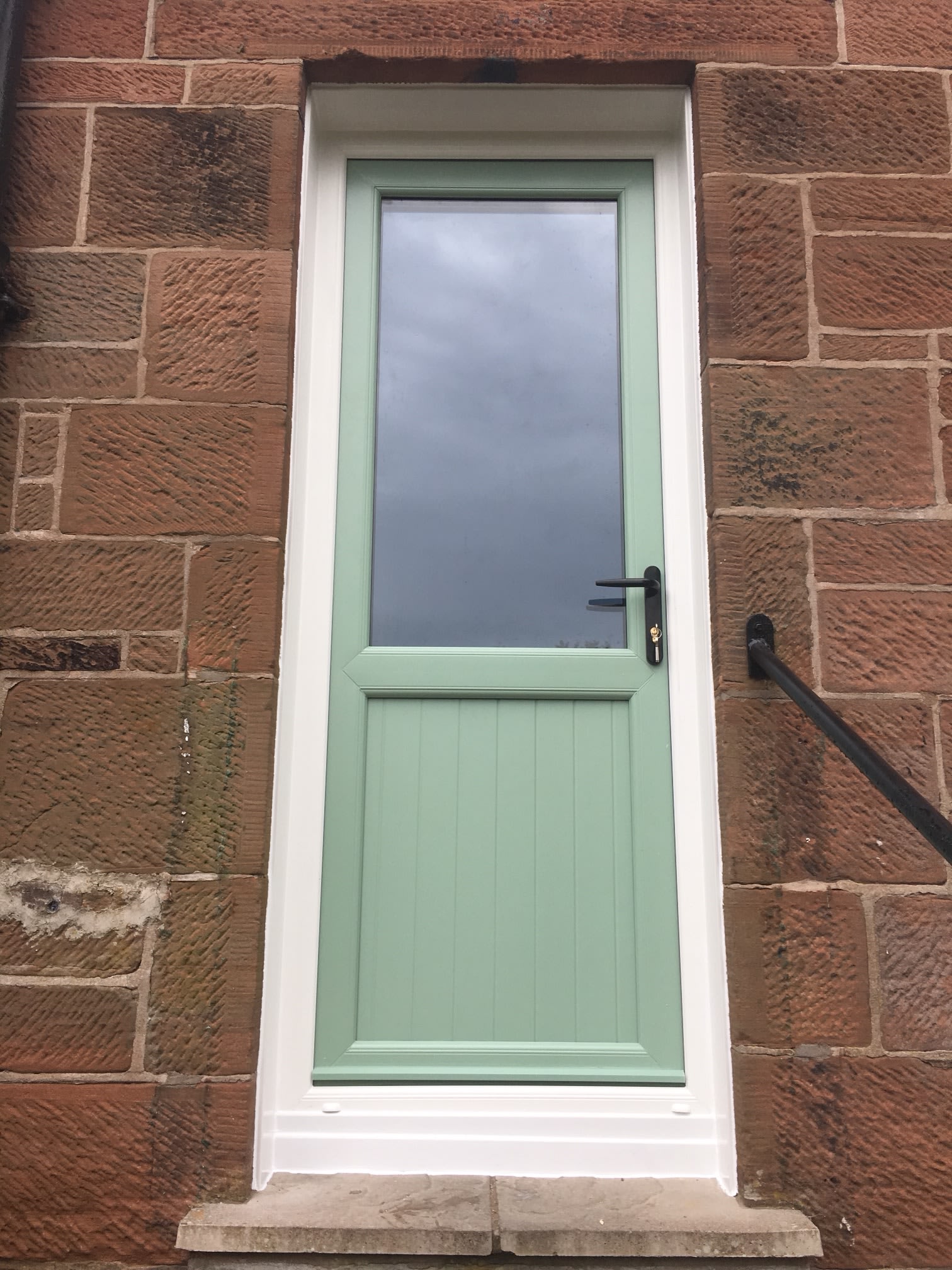 Sage-green door against traditional stonework.